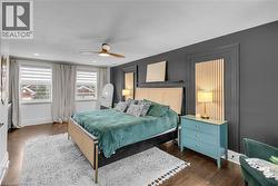 Dark wood-finish flooring, two large windows, ceiling fan, recessed lighting, and wall paneling - 