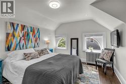 Vaulted ceiling with recessed lighting, dark wood-finish flooring, two distinct windows, and a built-in radiator - 