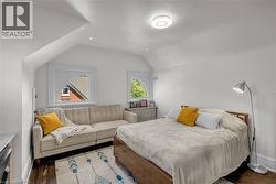 Sloped ceilings, wood-finish flooring, two large windows, recessed lighting, and a flush mount ceiling light - 