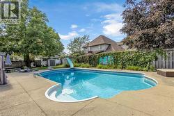 Expansive concrete patio surrounding a built-in swimming pool with an integrated slide - 