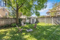 Expansive lawn area, mature shade tree, privacy fencing, storage shed, and stone-lined fire pit - 