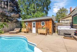 In-ground swimming pool, concrete patio, wood-paneled shed with octagonal windows, wooden privacy fencing, and an integrated hot tub - 