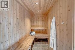 Sauna featuring wood-plank walls and ceiling, built-in wood benches, recessed lighting, and stone tile flooring - 