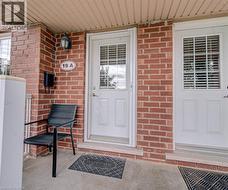 Brick exterior with a covered entryway, white entry door with integrated blinds, and an exterior wall light - 