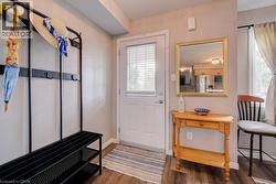 Wood-finish flooring throughout, bright white entryway door with integrated blinds, and a light-toned wood console table - 