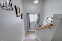 Stairwell featuring wood-finish flooring, a window with horizontal blinds, and a wood handrail - 