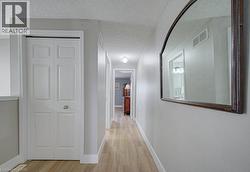 Hallway featuring wood-finish flooring, light gray walls, and a recessed ceiling light - 