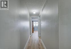 Hallway with wood-finish flooring, white trim, and a ceiling-mounted light fixture - 