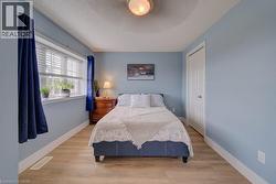 Wide window with blinds, light wood-finish flooring, white trim, and a white paneled door - 