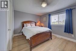 Light wood-finish flooring, white trim, window with blinds, and flush mount lighting - 