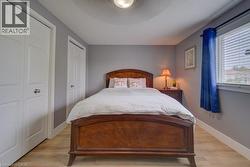 Wood-finish flooring, two paneled closet doors, window with blinds, and light gray wall paint - 