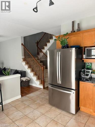 Stainless steel French door refrigerator, wood-finish cabinetry, black countertop, track lighting, and tiled flooring - 5383 Haldimand Crescent, Burlington, ON 