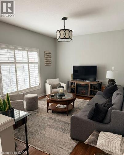 Vaulted ceiling featuring a decorative semi-flush mount light fixture, large windows with plantation shutters, and wood-finish flooring - 5383 Haldimand Crescent, Burlington, ON 