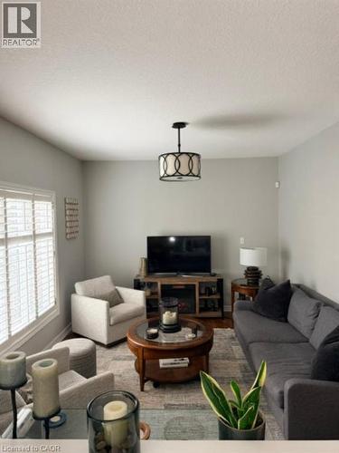 Recessed lighting and a decorative flush mount fixture illuminate this space, featuring wood-finish flooring and window shutters - 5383 Haldimand Crescent, Burlington, ON 