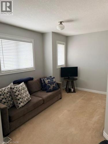 Carpeted flooring, multiple windows with blinds, a flush mount ceiling light, and neutral wall paint - 5383 Haldimand Crescent, Burlington, ON 