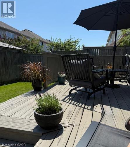 Wood-finish deck with integrated steps, surrounded by a wood privacy fence and a manicured lawn - 5383 Haldimand Crescent, Burlington, ON 