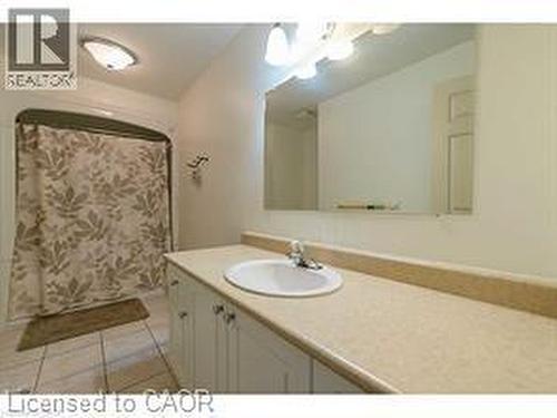 White vanity with lower cabinetry, integrated sink, chrome faucet, and a large wall-mounted mirror - 5383 Haldimand Crescent, Burlington, ON 