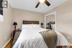 This room features wood flooring, a ceiling fan, and mirrored closet doors - 
