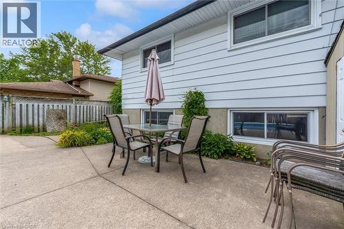 Concrete patio area featuring a white vinyl-sided exterior, upper-level casement window, lower-level sliding window, and surrounding perimeter landscaping - 7506 Jubilee Drive, Niagara Falls, ON 