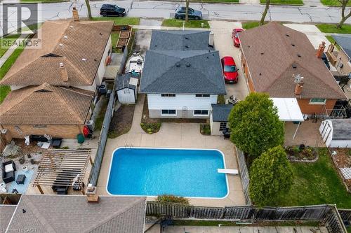 Backyard oasis featuring an in-ground swimming pool with diving board, concrete patio surround, and mature trees - 7506 Jubilee Drive, Niagara Falls, ON 
