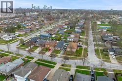 Aerial view showcasing the residential neighbourhood with a variety of homes, tree-lined streets, and a distant city skyline - 
