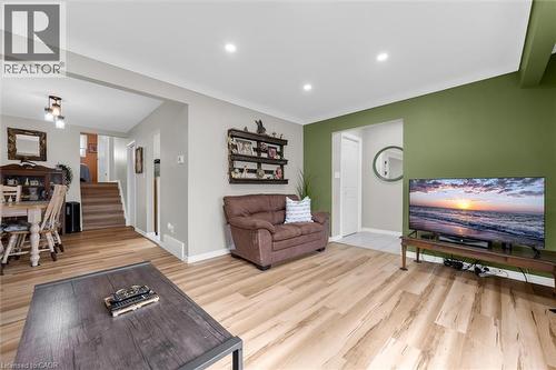 The property features light-toned wood flooring throughout the living area, complemented by a distinctive green accent wall - 7506 Jubilee Drive, Niagara Falls, ON 