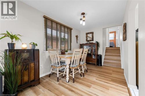 Dining area featuring wood-look flooring, a window with horizontal blinds, and a light fixture with three pendants - 7506 Jubilee Drive, Niagara Falls, ON 