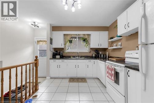 The kitchen features white cabinetry, dark countertops, and white tiled flooring - 7506 Jubilee Drive, Niagara Falls, ON 