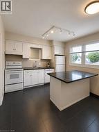 White cabinetry, dark countertops, track lighting, and a kitchen island - 