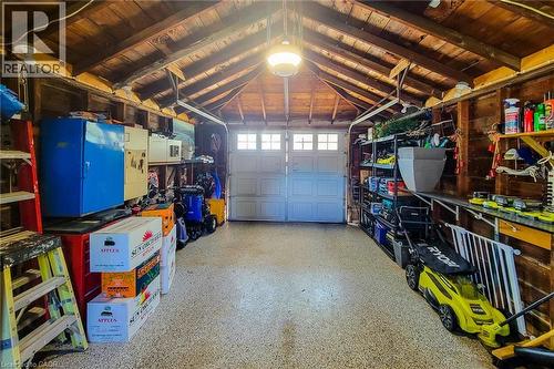 Exposed wood beam ceiling with lighting fixture, dual garage doors with window panes, and a speckled floor finish - 19 Thorndale Avenue, St. Catharines, ON 