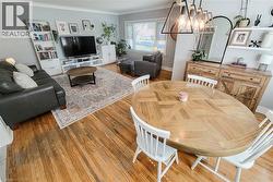 Hardwood flooring throughout, recessed window, built-in shelving, wood-finish console cabinet, and contemporary overhead light fixture - 
