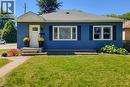 Blue horizontal siding exterior with a contrasting white front door, a gabled entry overhang, and white-framed windows with dark shutters - 19 Thorndale Avenue, St. Catharines, ON 