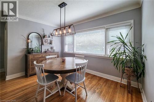 Hardwood flooring, multiple windows with blinds, built-in shelving, and a prominent linear chandelier - 19 Thorndale Avenue, St. Catharines, ON 