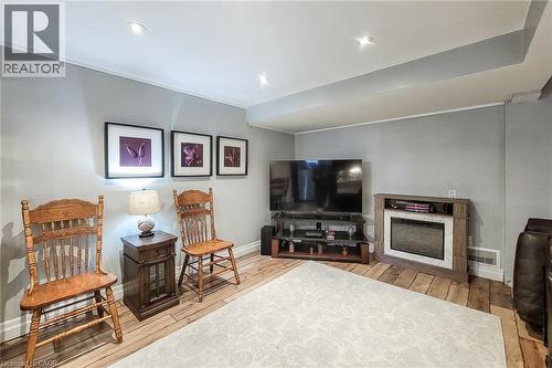 Recessed ceiling lighting, wood-finish flooring, electric fireplace with wood-finish surround, light gray wall paint, and white trim - 19 Thorndale Avenue, St. Catharines, ON 