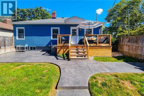 Blue siding exterior with a wood deck featuring black railing, a wood privacy fence, and a concrete patio - 19 Thorndale Avenue, St. Catharines, ON 