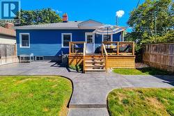 Blue siding exterior with a wood deck featuring black railing, a wood privacy fence, and a concrete patio - 