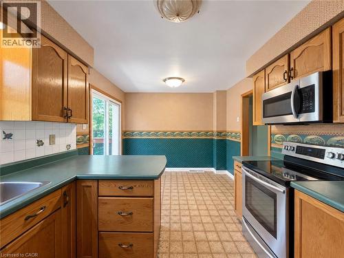 Kitchen featuring oak cabinetry, stainless steel appliances, a built-in microwave, and a glass-top range - 2490 Yarmouth Crescent, Oakville, ON 