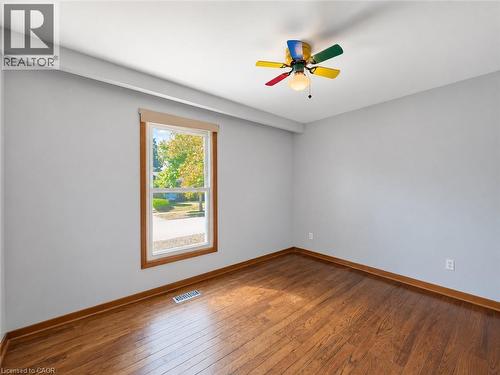Wood-finish flooring, single window with wood-frame trim, light gray wall finish, and a ceiling fan with multi-colored blades - 2490 Yarmouth Crescent, Oakville, ON 