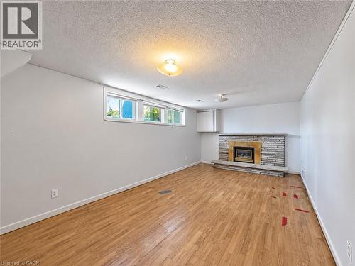 Wood-finish flooring, stone-clad fireplace with hearth, white walls, and built-in upper cabinetry - 2490 Yarmouth Crescent, Oakville, ON 
