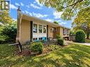 Brick exterior featuring a front entry with a transom window, an attached garage, a front porch with an iron railing, and mature landscaping - 2490 Yarmouth Crescent, Oakville, ON 