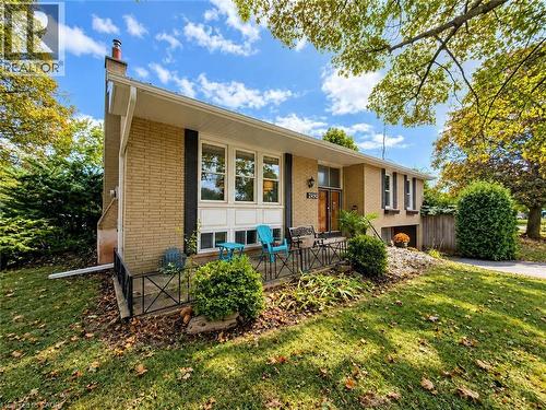 Brick exterior featuring a front entry with a transom window, an attached garage, a front porch with an iron railing, and mature landscaping - 2490 Yarmouth Crescent, Oakville, ON 