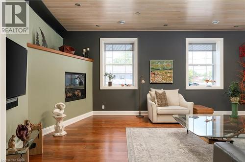 Hardwood flooring, recessed lighting, built-in electric fireplace, wall-mounted display ledge, and multiple windows with white trim - 23 Market Street W, Port Dover, ON 