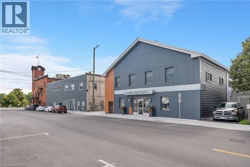 Modern facade with horizontal siding, large storefront windows, and prominent signage - 23 Market Street W, Port Dover, ON 