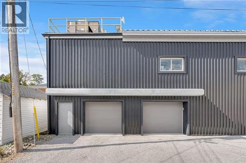 Corrugated metal facade with multiple windows, two garage doors, and a pedestrian door - 23 Market Street W, Port Dover, ON 