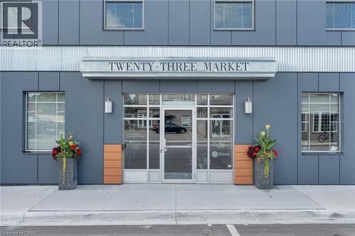 Modern building facade with gray paneling, prominent ""TWENTY-THREE MARKET"" signage, and large glass entry doors - 23 Market Street W, Port Dover, ON 