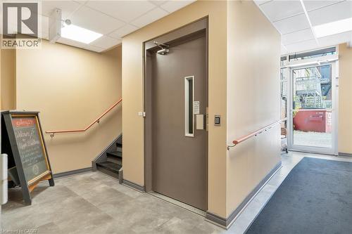 Secured entry door with keypad access, commercial-grade flooring, staircase with wood handrail, and recessed ceiling lighting - 23 Market Street W, Port Dover, ON 