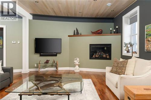 Hardwood flooring, wood-paneled ceiling with recessed lighting, fireplace with a wood mantle, white trim, and a window with a deep sill - 23 Market Street W, Port Dover, ON 