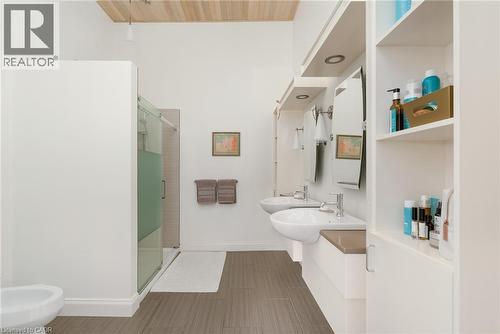 Dual floating vanities with integrated vessel sinks, extensive built-in shelving, glass-enclosed shower, and wood-finish ceiling - 23 Market Street W, Port Dover, ON 