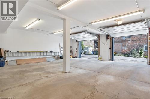 Two overhead garage doors, concrete flooring, exposed support beams, and fluorescent lighting - 23 Market Street W, Port Dover, ON 