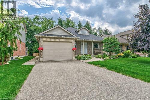 Brick and siding exterior featuring a single-car garage, dormer window, and mature landscaping - 423 Poldon Drive, Norwich, ON 